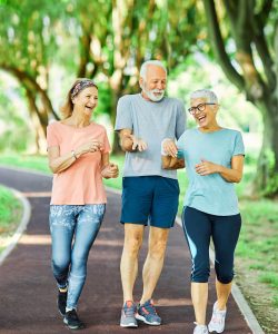Smiling active senior people jogging together in the park
